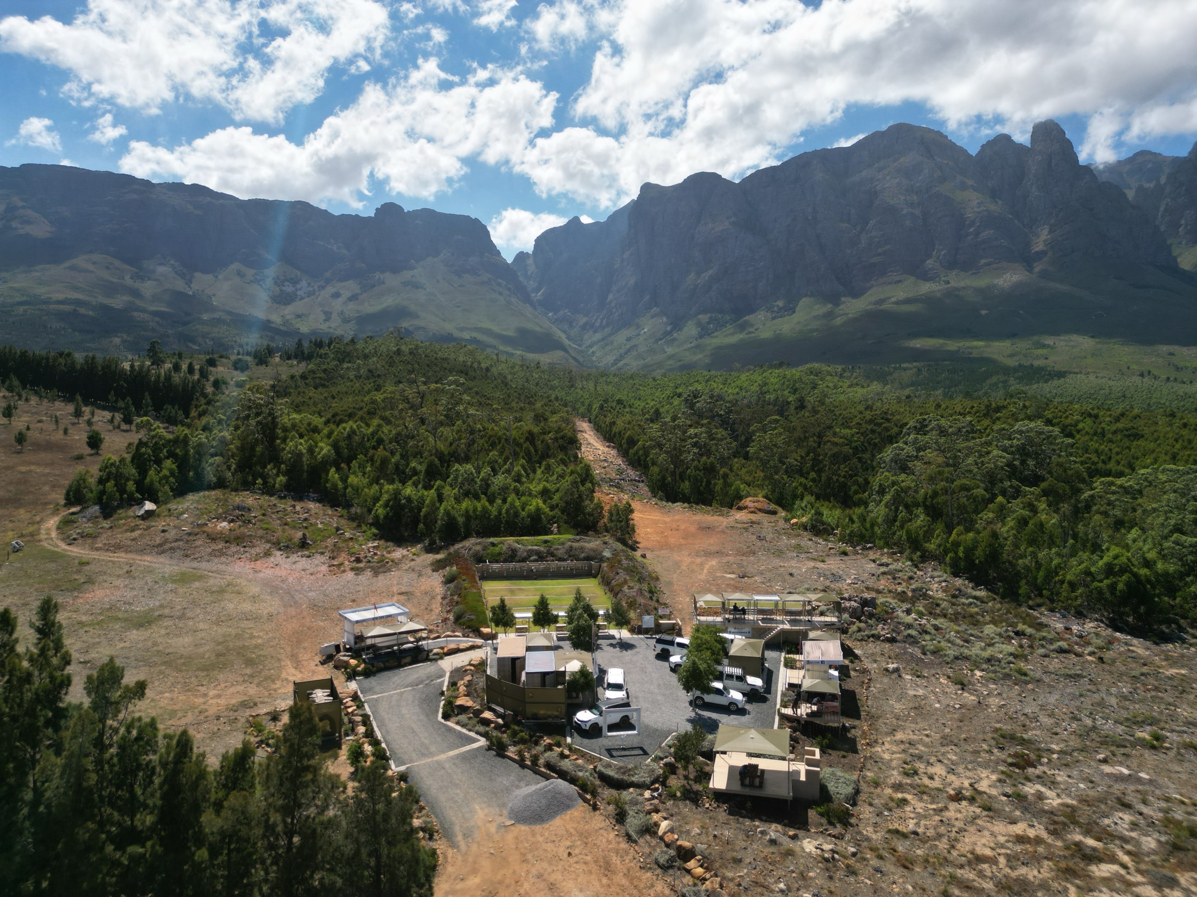 Aerial view of the range on Lourensford: shooting platforms and a cleared long-range corridor running up the valley, with the Helderberg mountains behind.